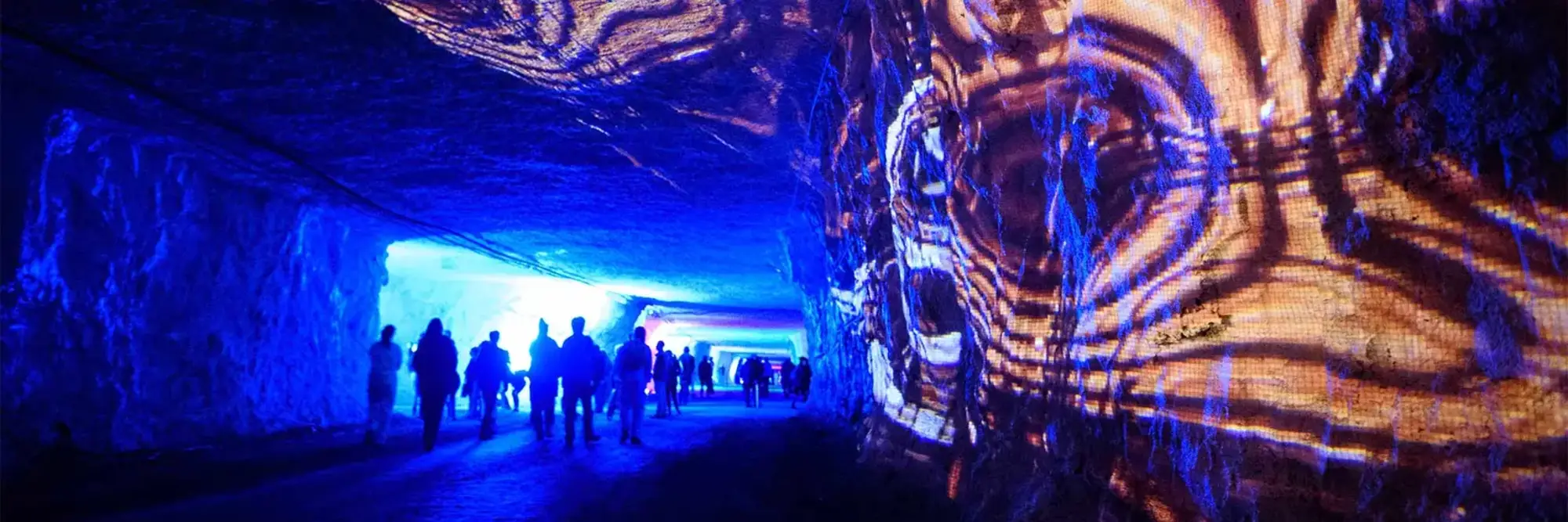 Lights projected against the wall of a cave, with the silhouettes of many people.