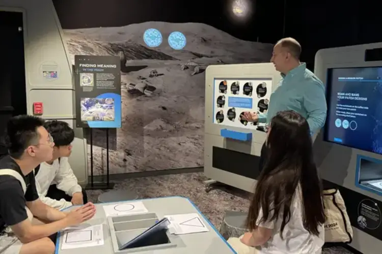 Four people gathered around a display, surrounded by a moonscape.
