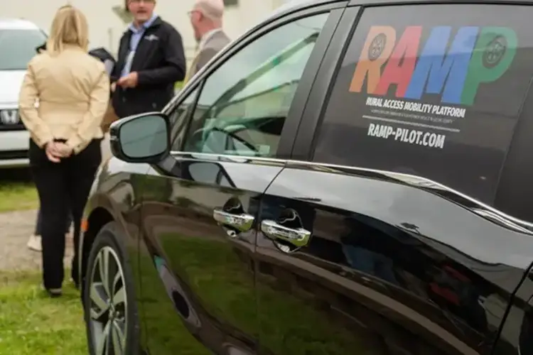 Image of a car with a group of people in the background.