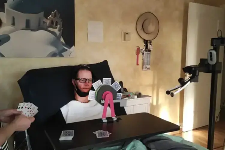 Person using assistive technology to play cards.